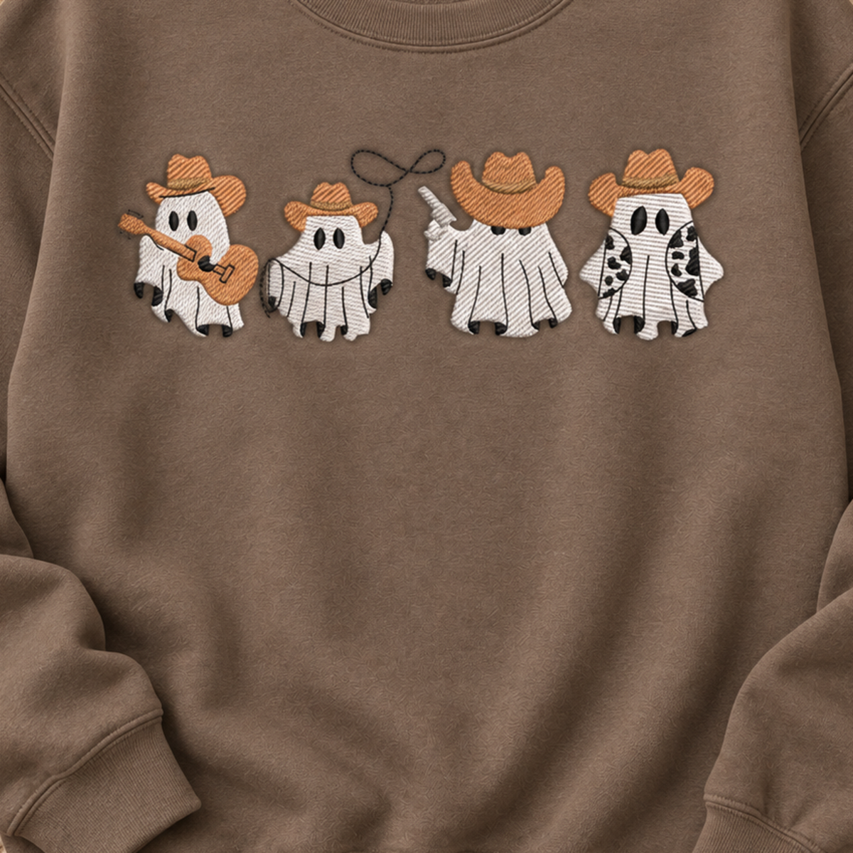 Close-up of four western cowboy ghosts embroidered across a Brown Savanna sweatshirt