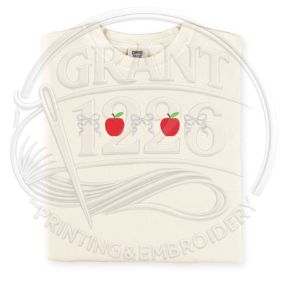 Ivory embroidered teacher shirt with red apples and coquette bow design on Comfort Colors tee
