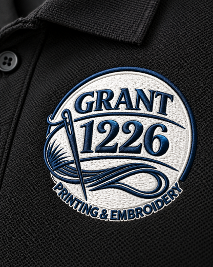 Close-up of navy and white Grant 1226 logo embroidery on black pique work polo