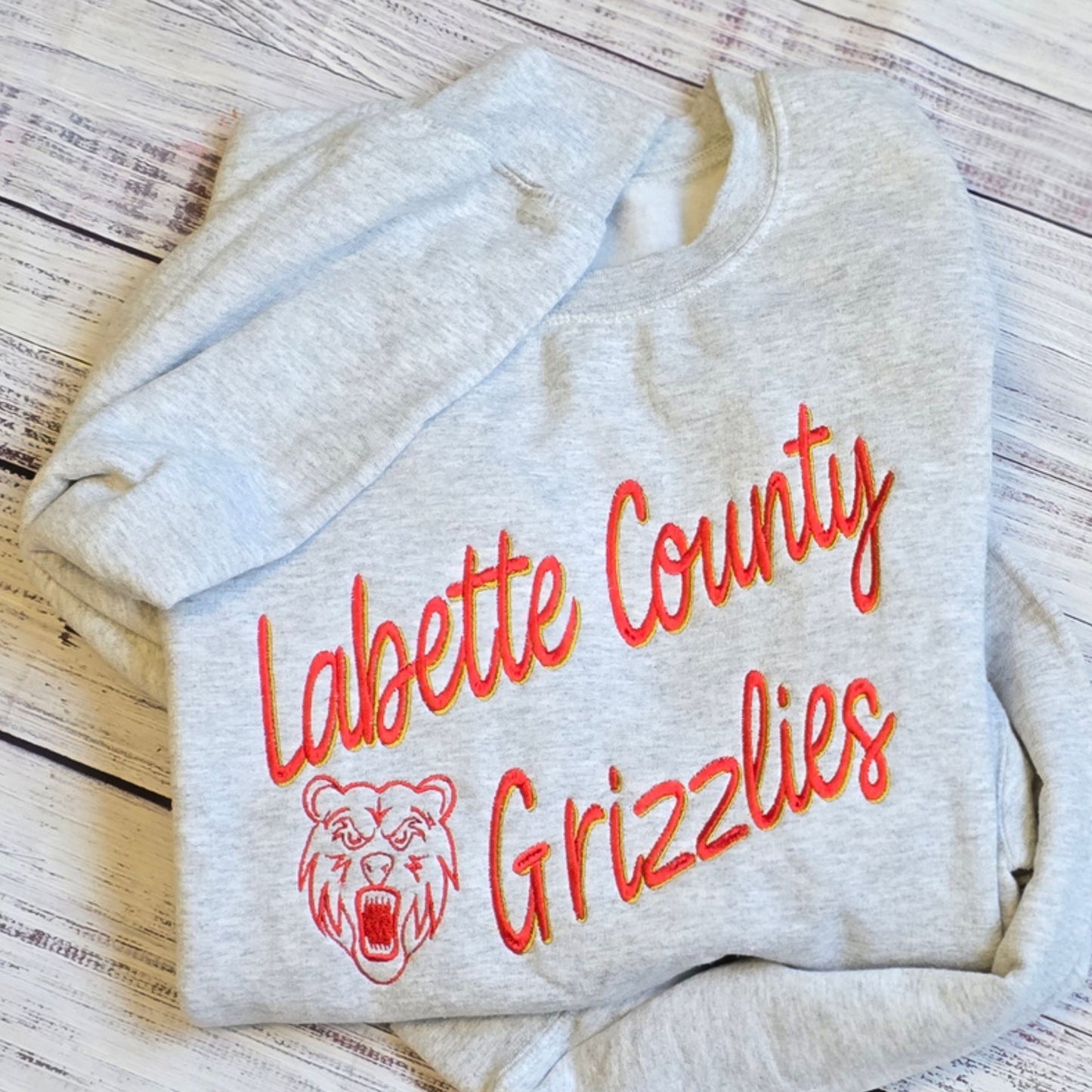 Custom shadow embroidered sweatshirt on ash gray crewneck featuring sports team sample design. 