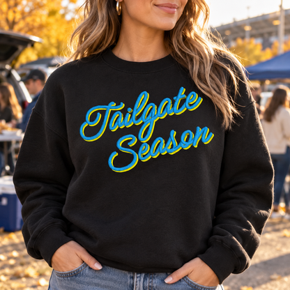 Black embroidered Tailgate Season sweatshirt with blue and yellow custom thread shown at an autumn game day tailgate