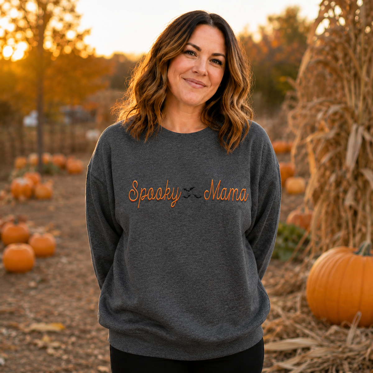 Woman wearing Dark Heather Spooky Mama embroidered Halloween sweatshirt at a pumpkin patch