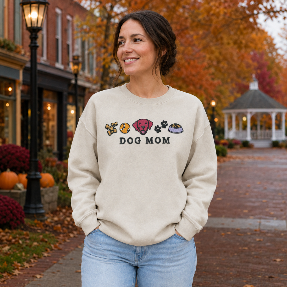 Dog Mom embroidered Sand Gildan Softstyle sweatshirt on a fall town street