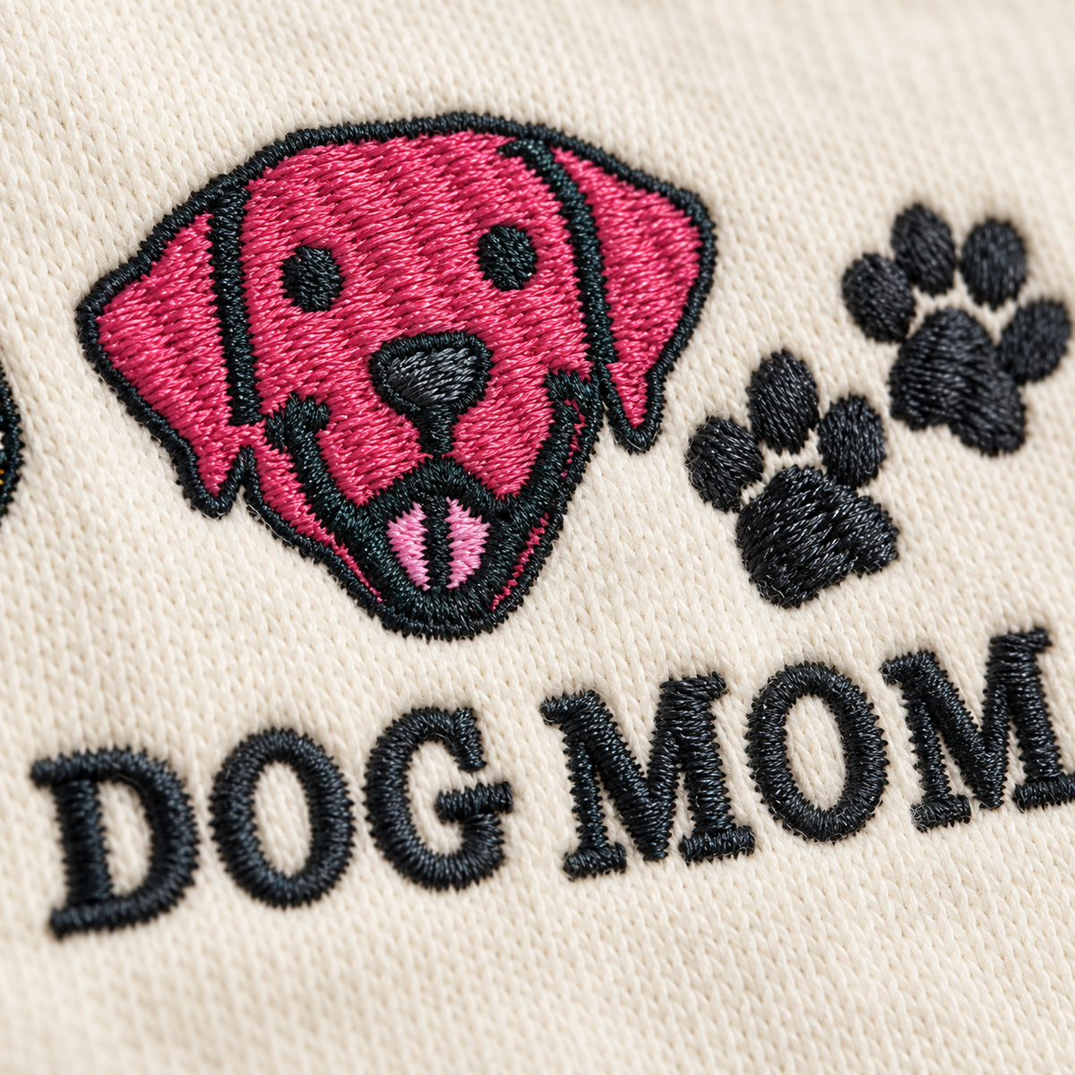 Close-up of pink dog and paw print embroidery stitches on Ivory fabric