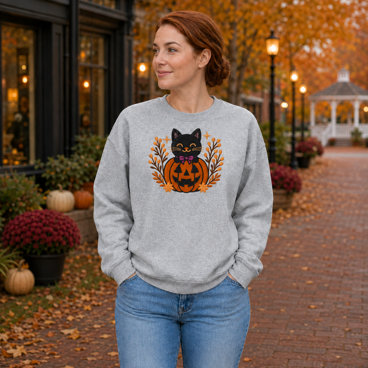 Sport Grey embroidered sweatshirt with black cat in jack-o-lantern Halloween design on an autumn town-square model mockup