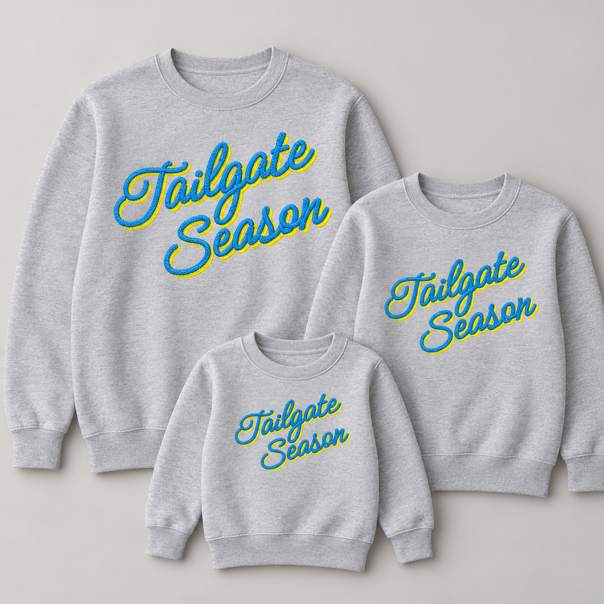 Adult youth and toddler grey crewneck sweatshirts showing proportional Tailgate Season embroidery sizing