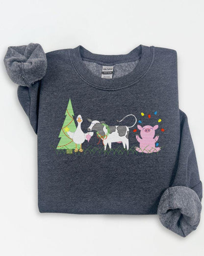Close-up of the festive farm animal embroidery stitched on a holiday sweatshirt.