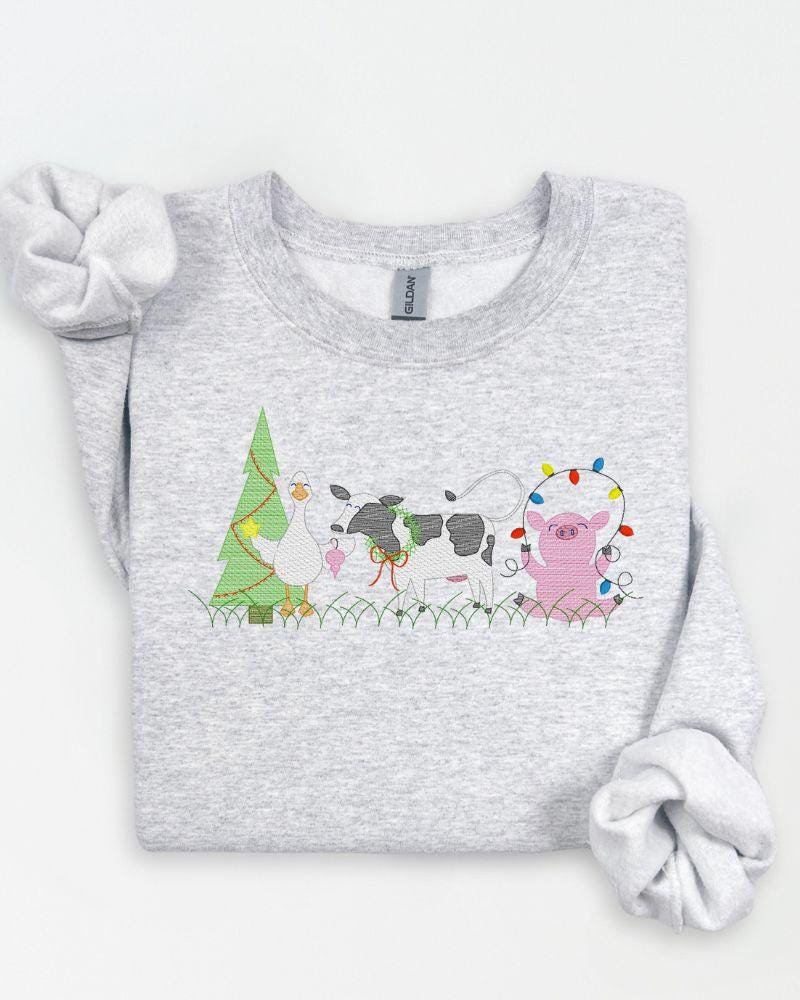 Farm animal embroidered Christmas sweatshirt styled in a rustic holiday flat lay.