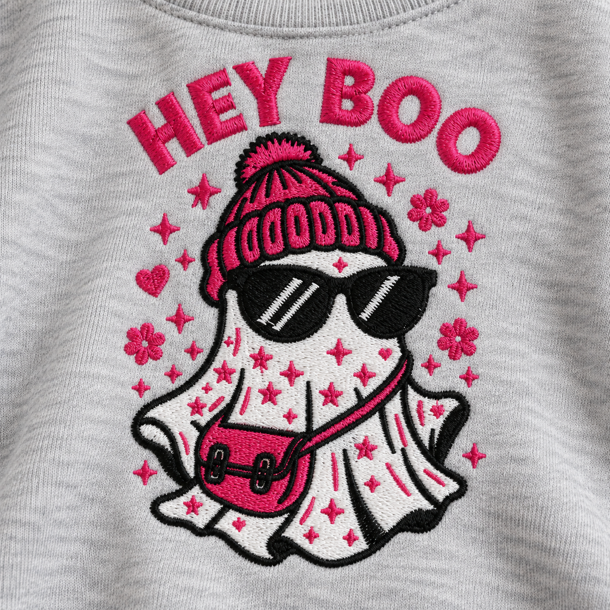 Close-up of pink black and white fashion ghost embroidery on ash sweatshirt fabric