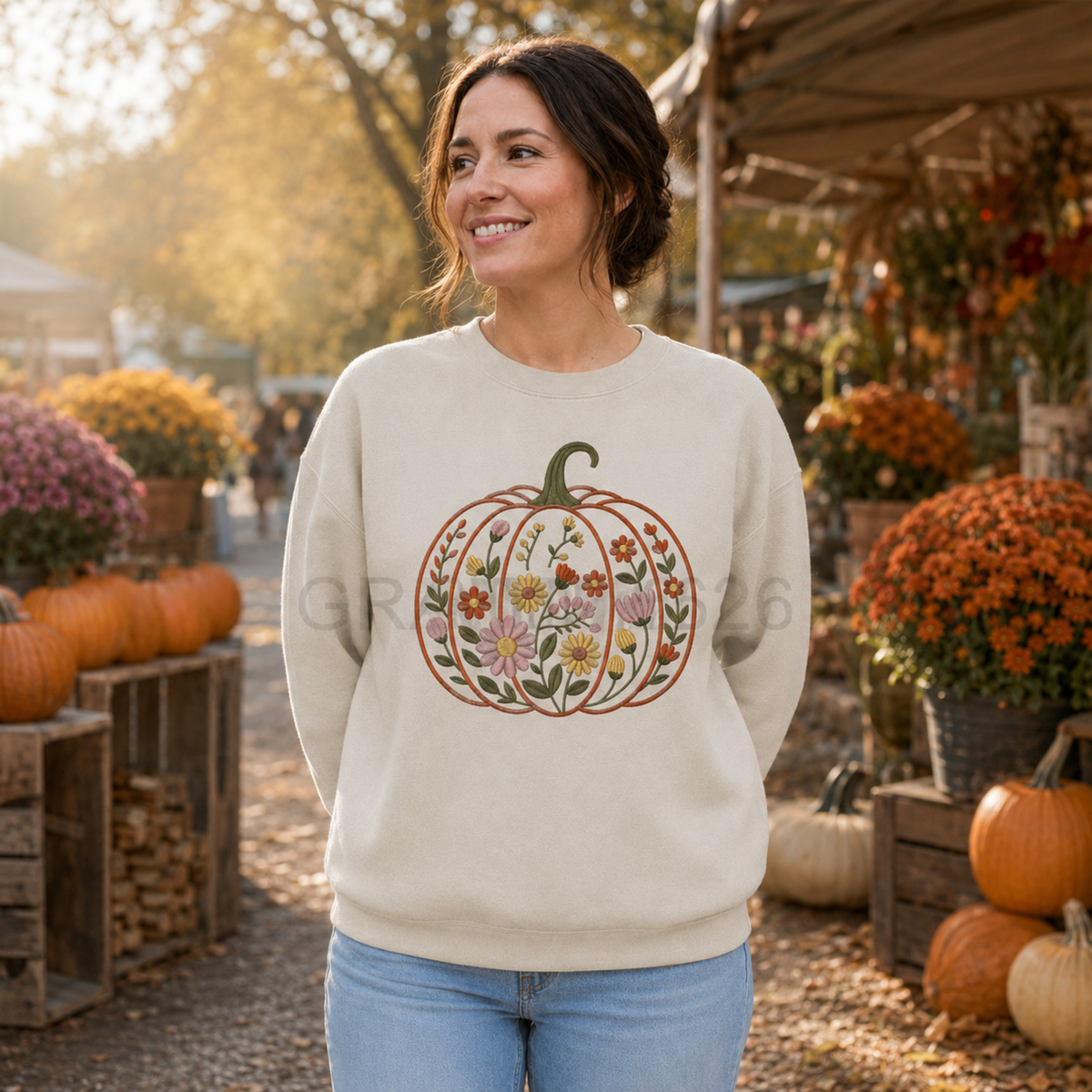 Woman wearing a Sand Gildan Softstyle floral garden pumpkin embroidered sweatshirt at a fall farmers market