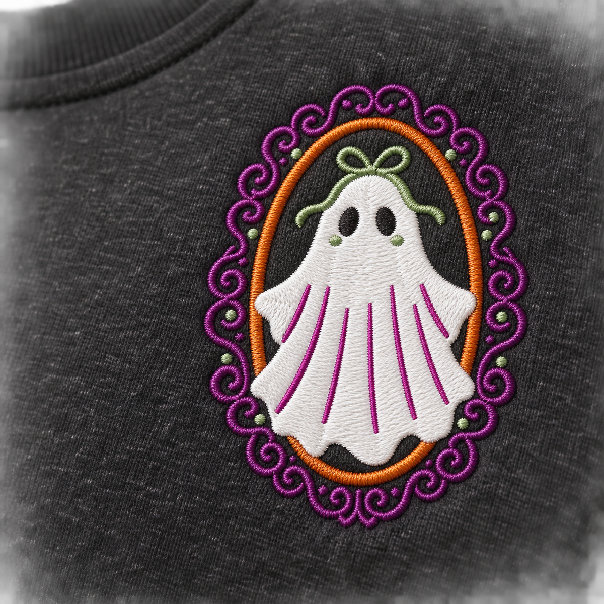 Macro detail of white, black, burnt-orange, plum-purple, and sage-green embroidery on heathered-black sweatshirt fabric.