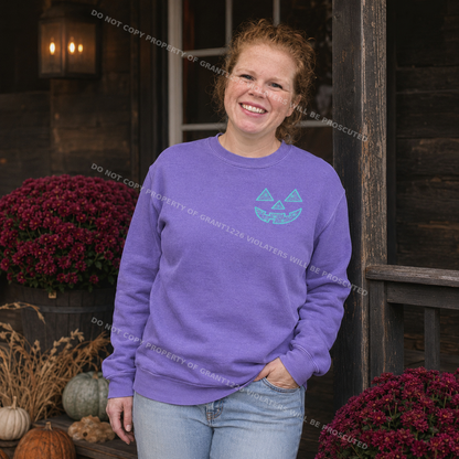 Woman wearing violet Comfort Colors geometric jack-o-lantern embroidered sweatshirt in a moody fall porch setting