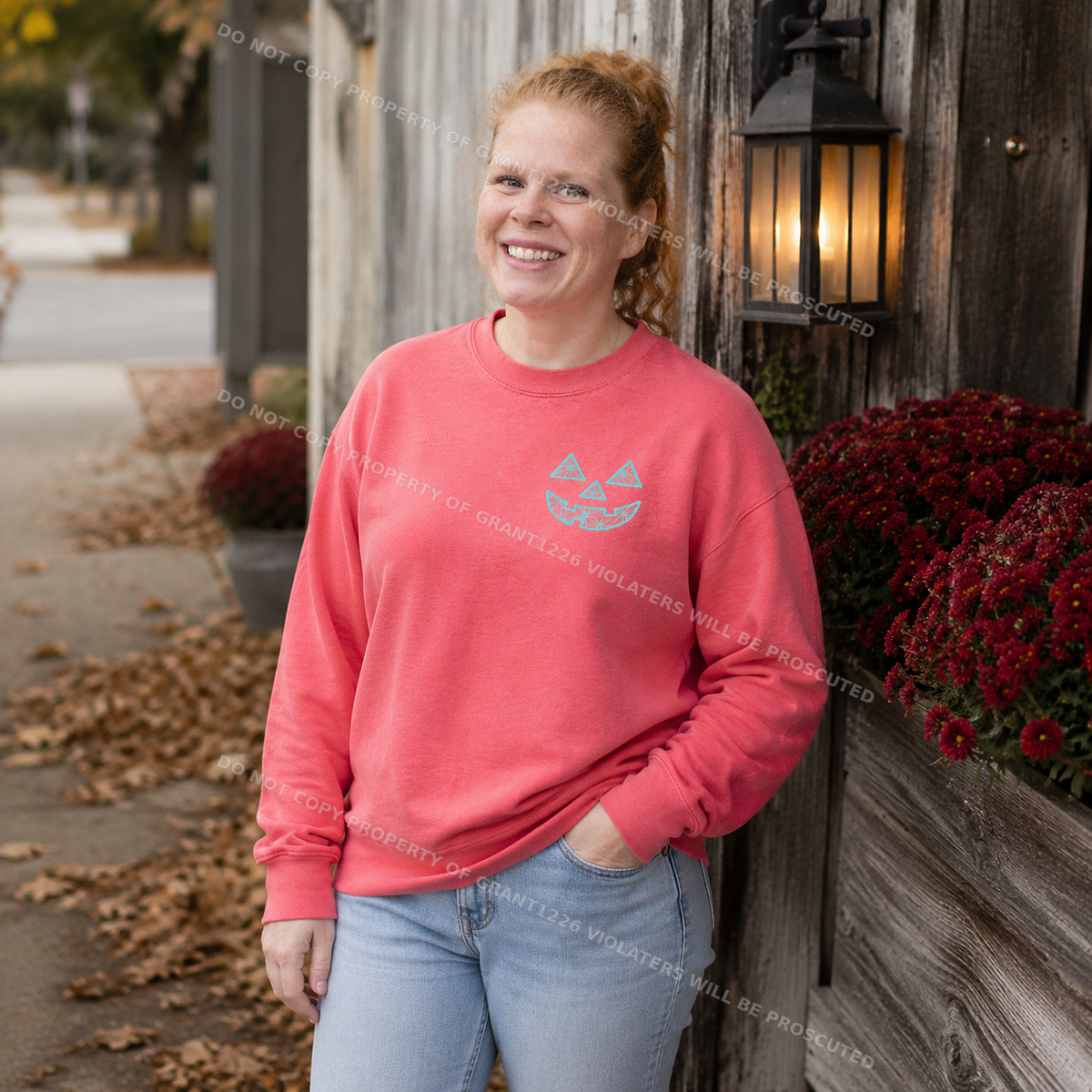 Woman wearing watermelon Comfort Colors geometric jack-o-lantern embroidered sweatshirt in a small-town fall scene