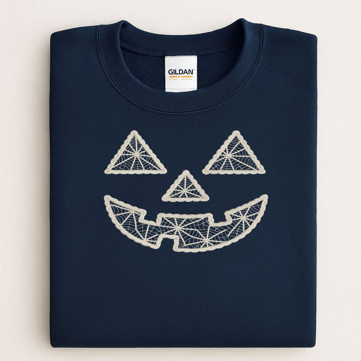 Folded navy crewneck with geometric pumpkin face embroidery