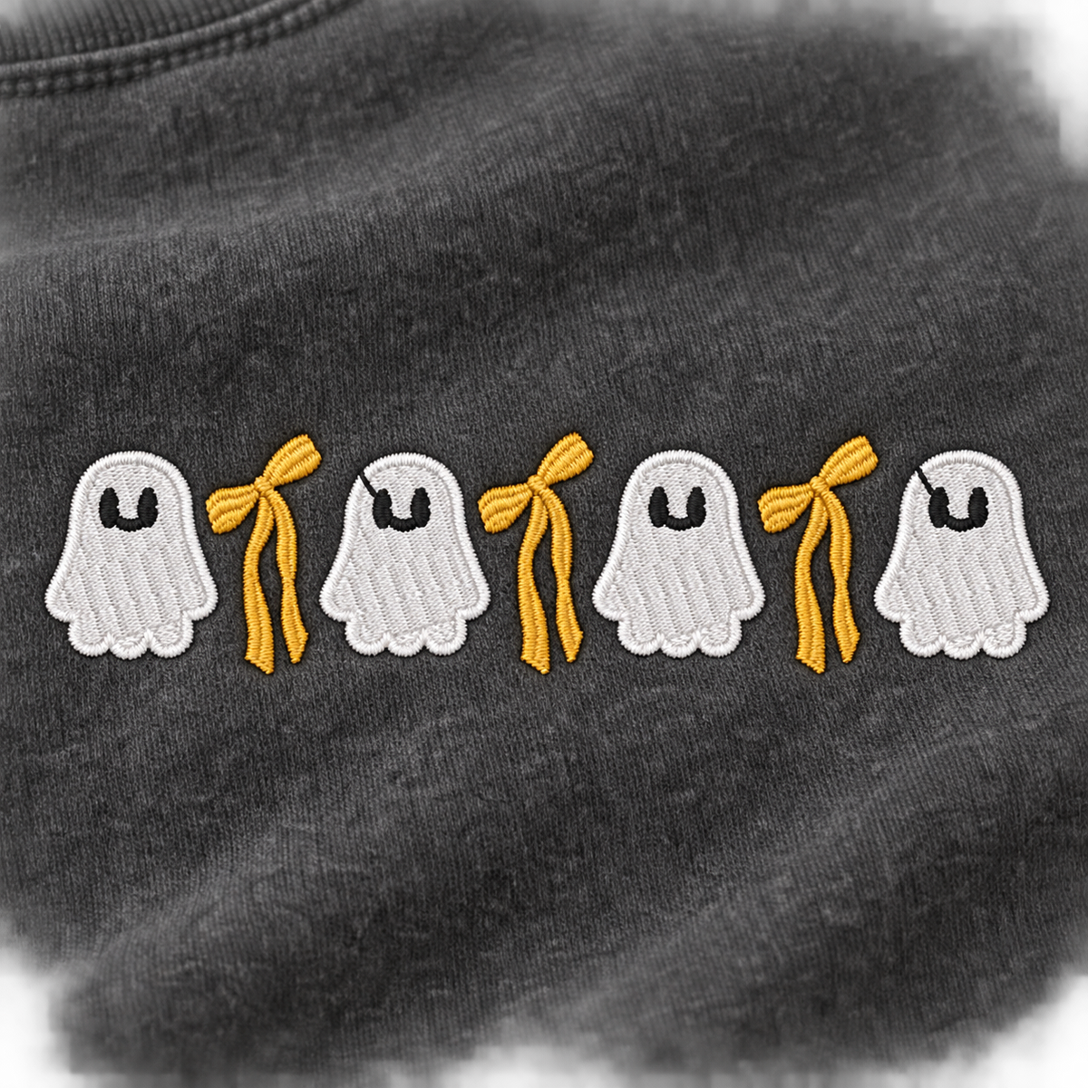Close-up of four white ghosts and three golden bows embroidered on Pepper sweatshirt fleece