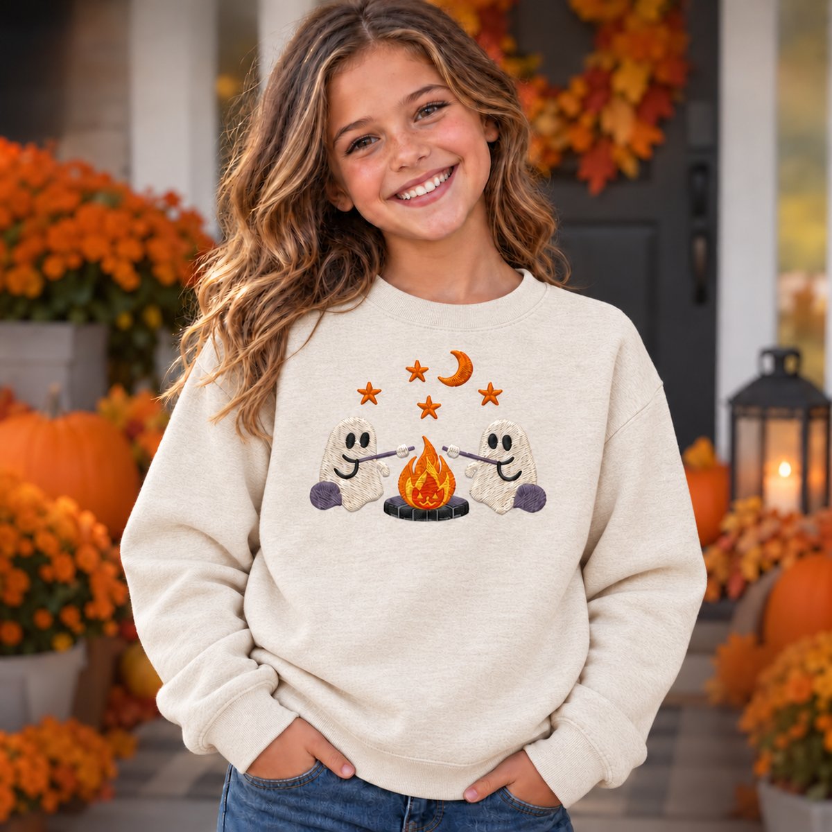 Youth wearing a Natural embroidered ghost campfire sweatshirt with two ghosts roasting marshmallows