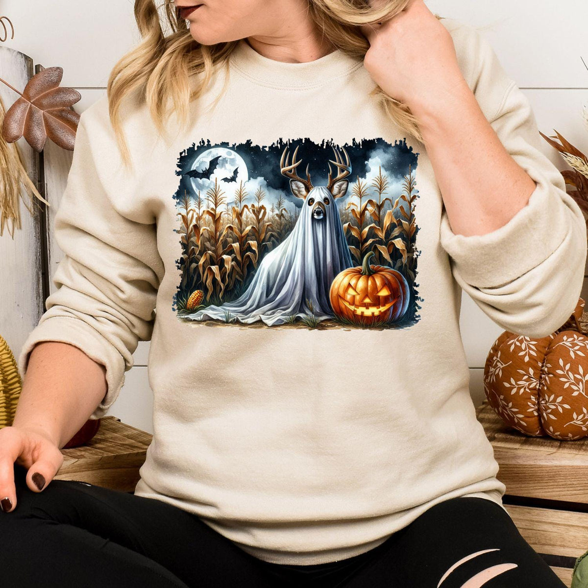 Sand ghost deer and pumpkin Halloween graphic sweatshirt modeled indoors