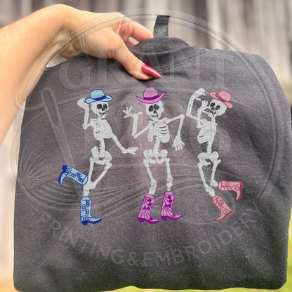 Black Gildan Heavy Blend sweatshirt with embroidered dancing cowgirl skeletons in colorful hats and boots