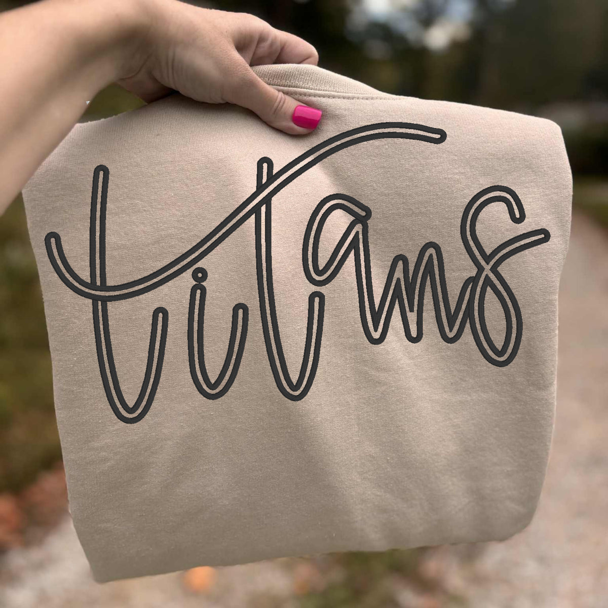 Close-up of black Titans puff embroidery on sand Gildan sweatshirt showing raised stitched detail