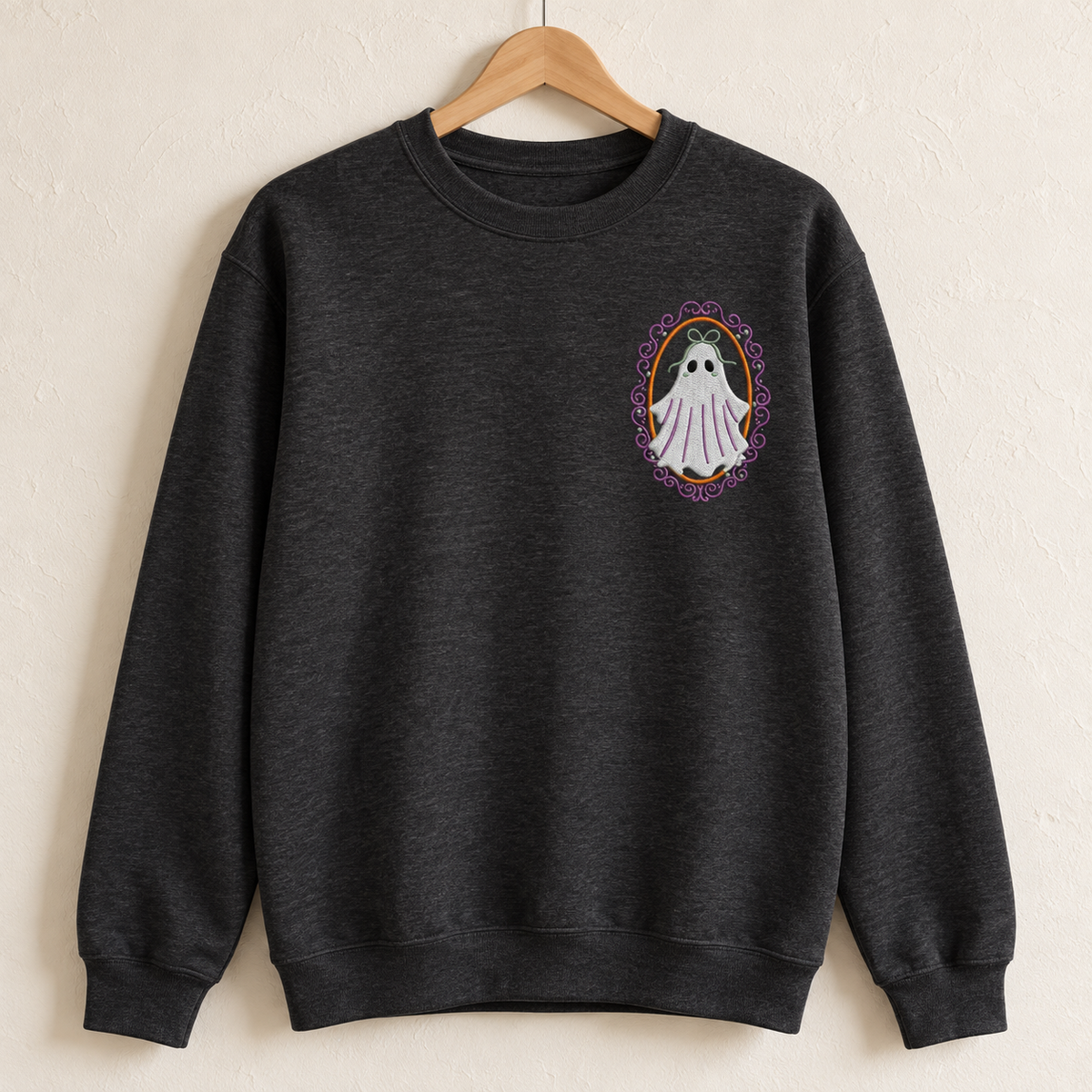 Heathered-black Gildan Softstyle crewneck on a wooden hanger showing the embroidered ghost over the left chest.