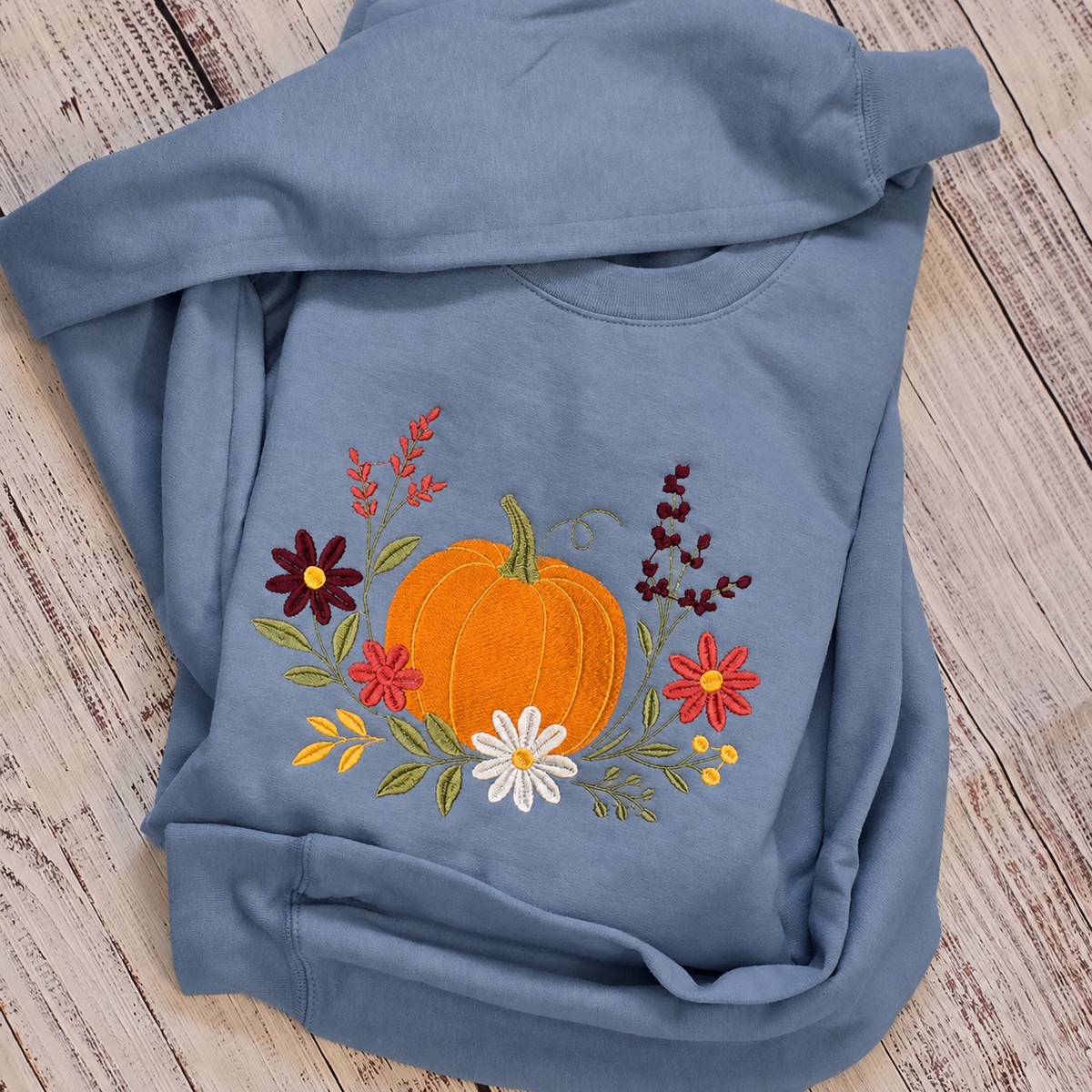 Stone Blue floral pumpkin embroidered Gildan Softstyle sweatshirt folded view
