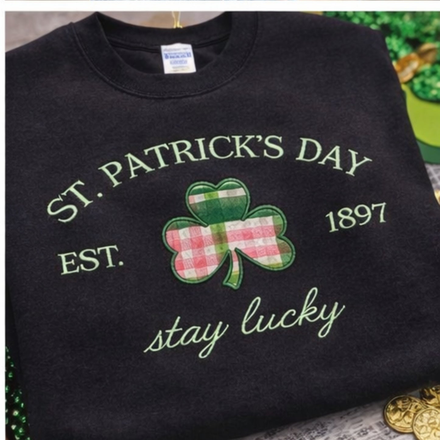 Black sweatshirt with St. Patrick's Day design featuring a shamrock and text on a textured surface.