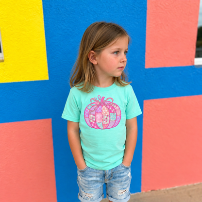 Girl wearing a Saltwater LAT youth shirt with a pink patchwork bow pumpkin DTG design