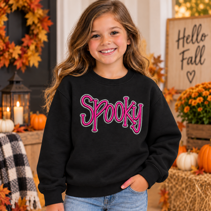Girl wearing a black youth Spooky puff embroidered sweatshirt with pink and silver thread