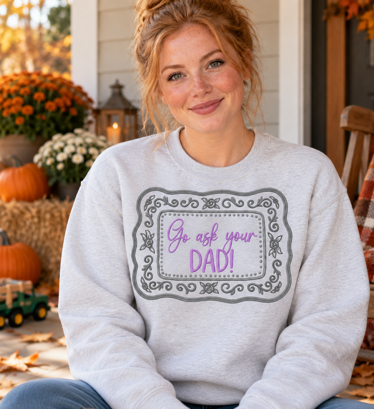 Woman wearing an Ash Gildan Softstyle embroidered Go Ask Your Dad sweatshirt with lavender and grey floral frame