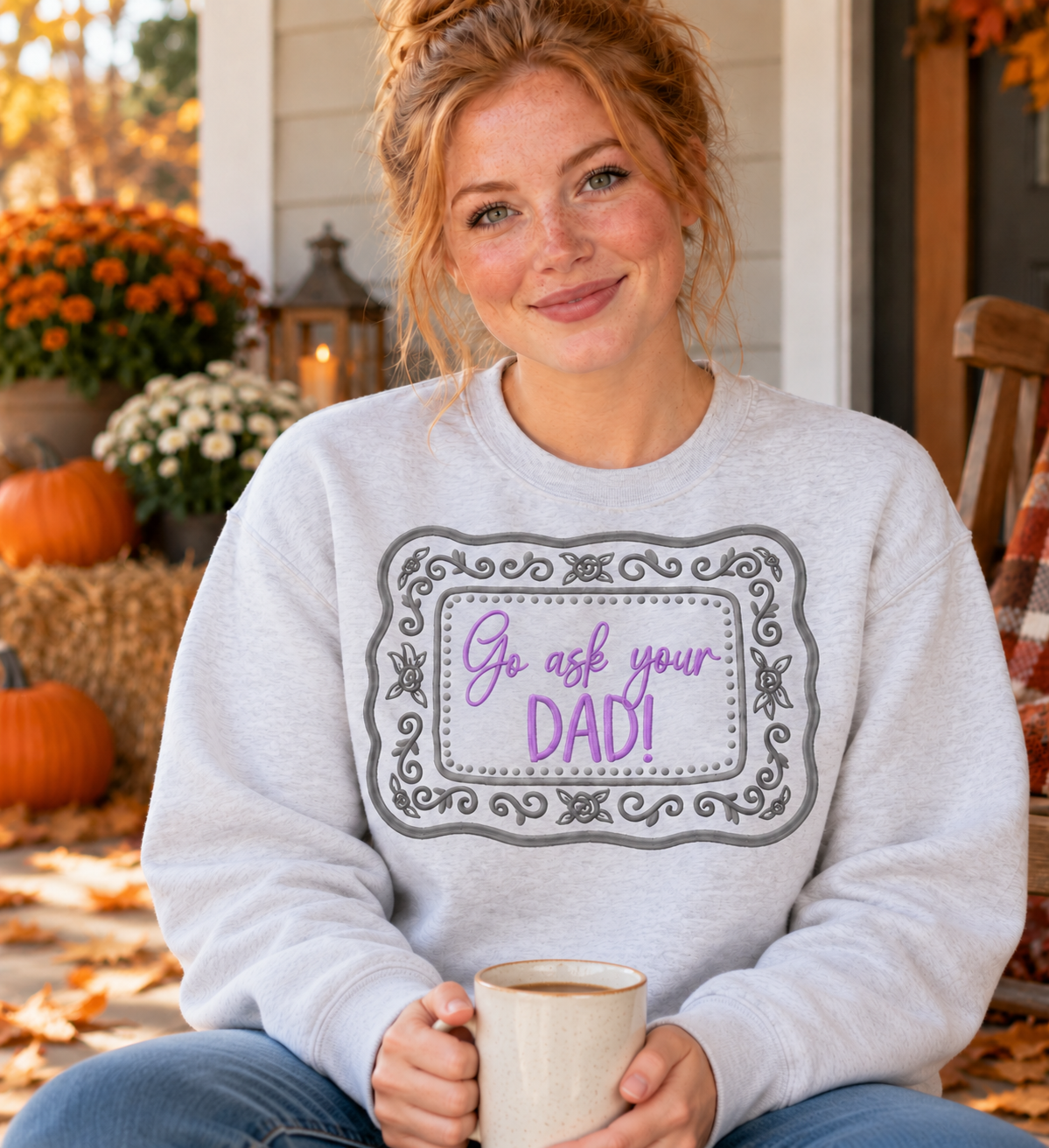 Woman in Ash Go Ask Your Dad embroidered sweatshirt holding coffee on a fall porch
