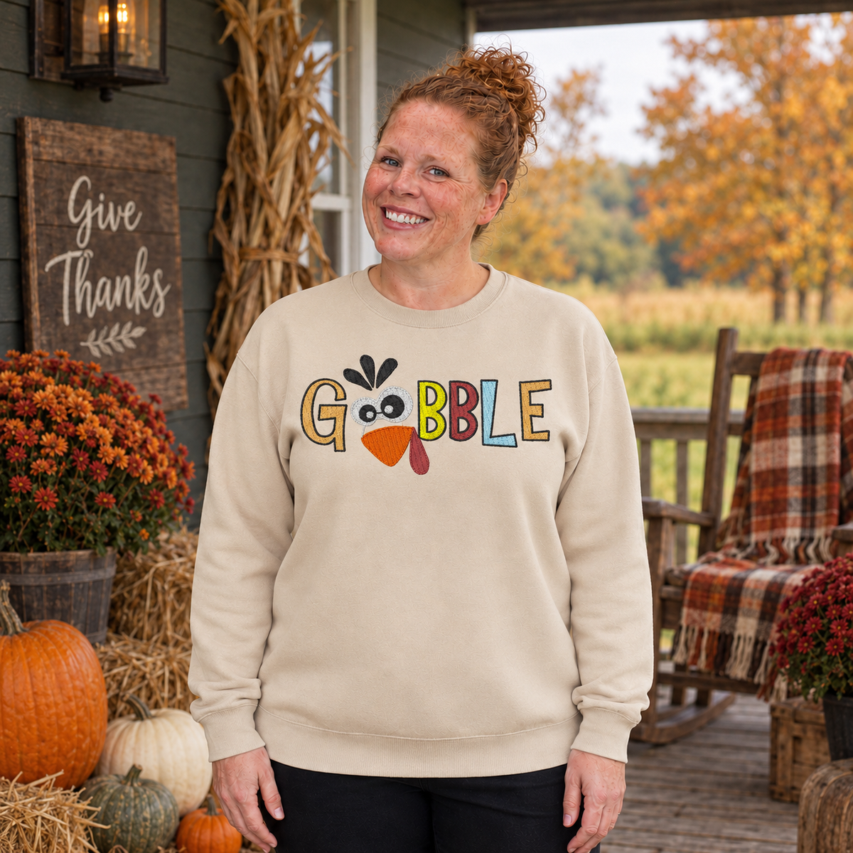 Samantha wearing a Sand Gobble turkey embroidered Thanksgiving sweatshirt on a rustic fall porch