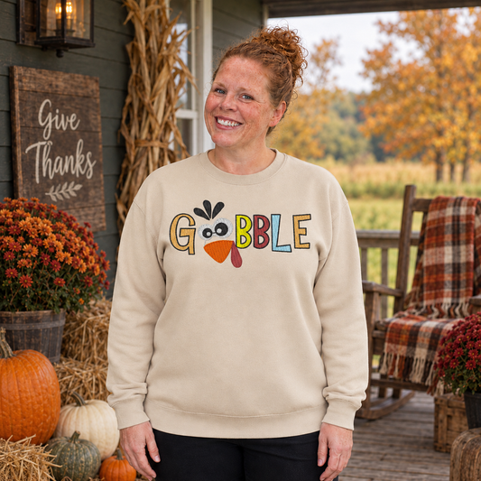 Samantha wearing a Sand Gobble turkey embroidered Thanksgiving sweatshirt on a rustic fall porch