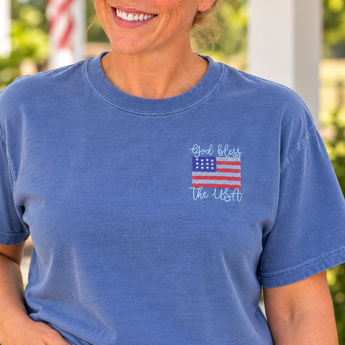 Close-up of raised God Bless the USA flag embroidery on a Blue Jean Comfort Colors tee