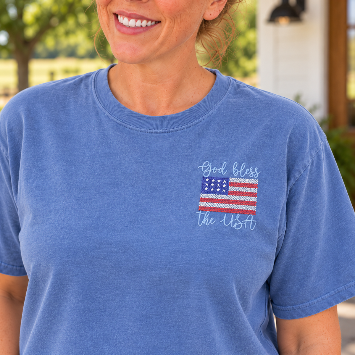 Close-up of raised God Bless the USA flag embroidery on a Chambray Comfort Colors tee