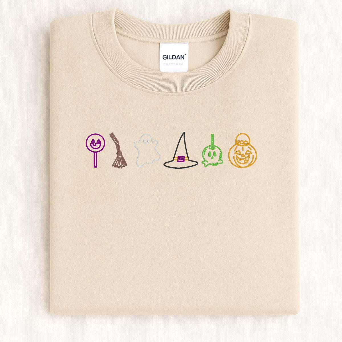 Sand sweatshirt with colorful embroidered Halloween candy icons folded flat