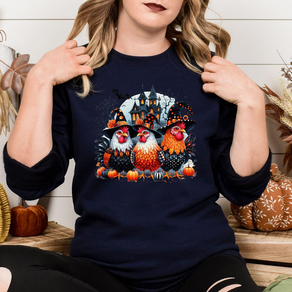 Navy sweatshirt with spooky chickens and haunted house graphic modeled indoors