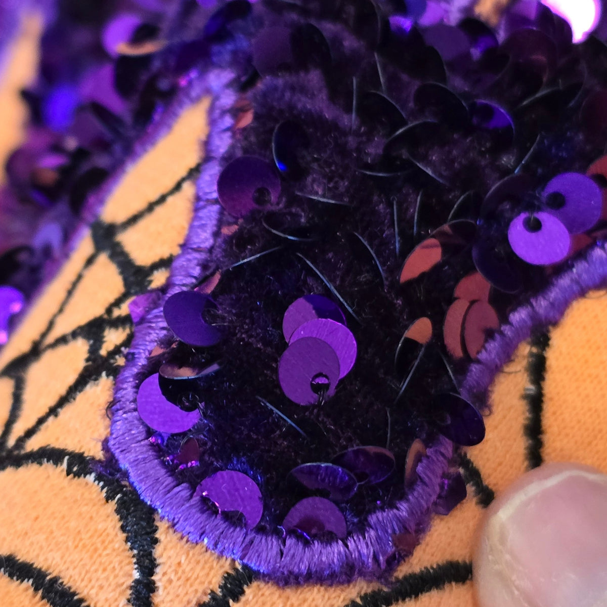 Close-up of purple and black sequin-on-velvet MAMA appliqué with purple satin-stitch edging