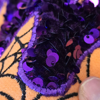 Close-up of purple and black sequin-on-velvet MAMA appliqué with purple satin-stitch edging