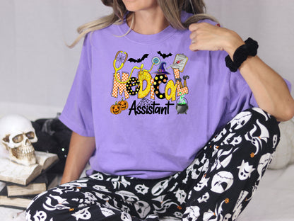 Close lifestyle view of a Violet Comfort Colors tee with colorful Halloween Medical Assistant artwork.