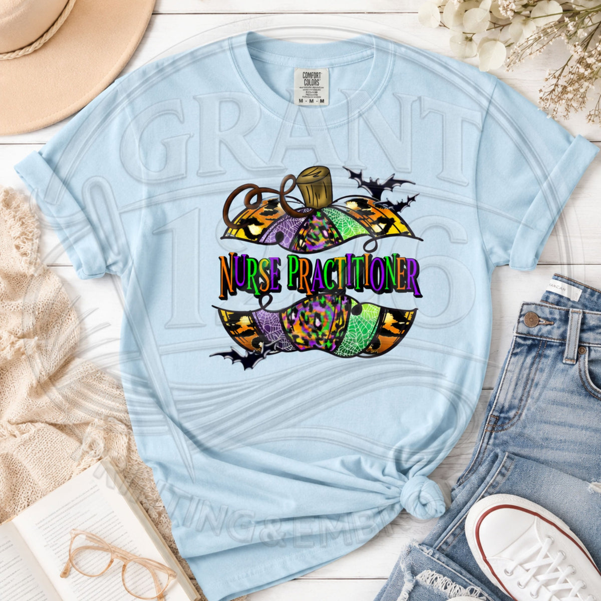 Chambray Comfort Colors short sleeve Nurse Practitioner Halloween shirt with colorful pumpkin and bats graphic, flat lay.