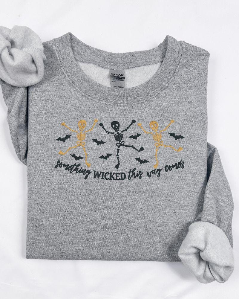 Halloween crewneck featuring embroidered skeletons, flying bats and Something Wicked phrase