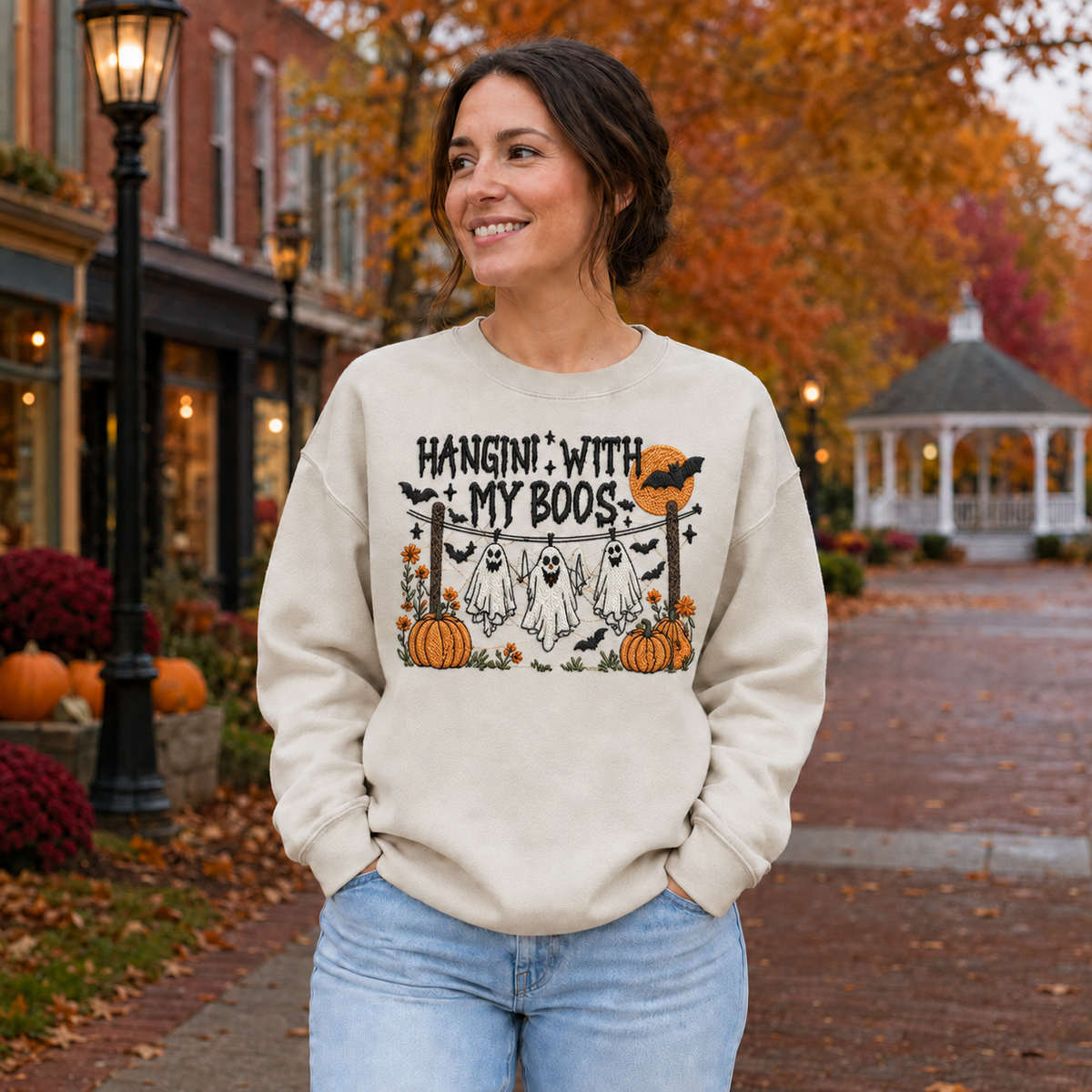 Woman wearing a Sand Hanging With My Boos embroidered Halloween sweatshirt with ghosts and pumpkins