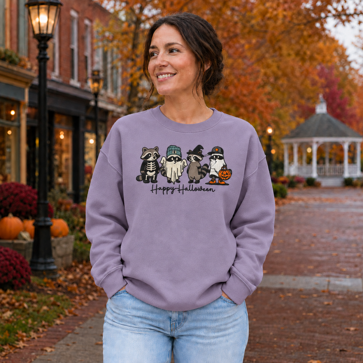 Adult wearing a Paragon purple embroidered Happy Halloween raccoon sweatshirt with four costumed raccoons