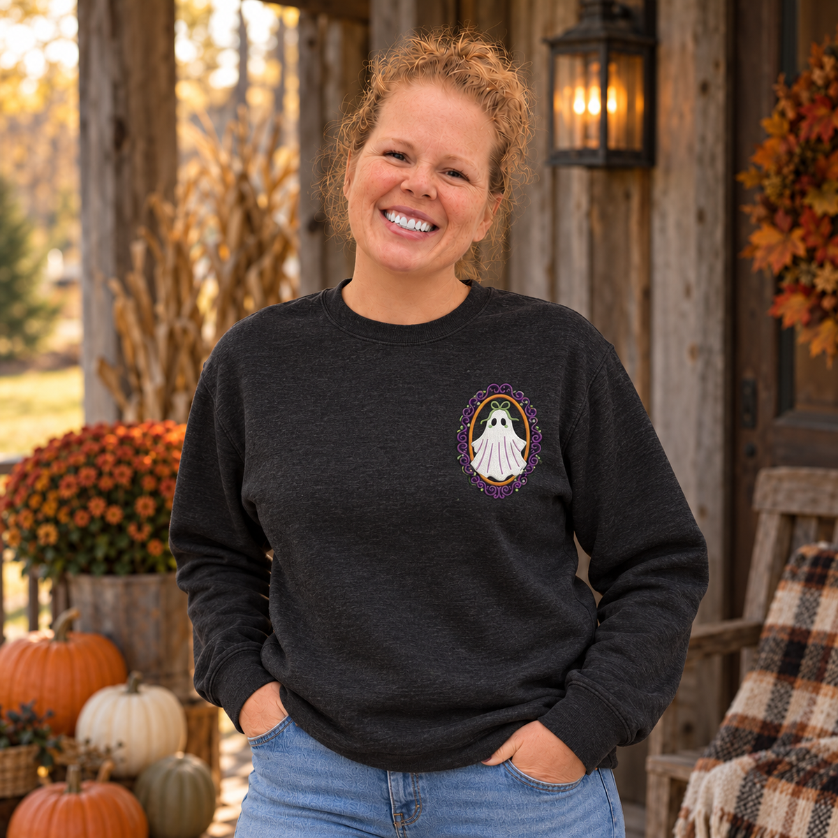 Front lifestyle view of a heathered-black sweatshirt with a white ghost, black eyes, sage bow, orange oval, and plum frame embroidered on the left chest.