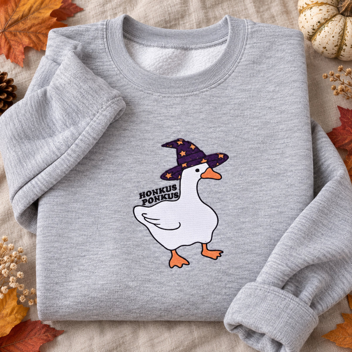 Close view of Honkus Ponkus witch goose embroidery on an Ash sweatshirt