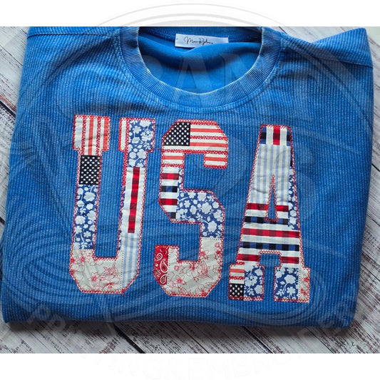 Patriotic USA applique sweatshirt in bright blue corded fabric shown folded with red white and blue patchwork letters.