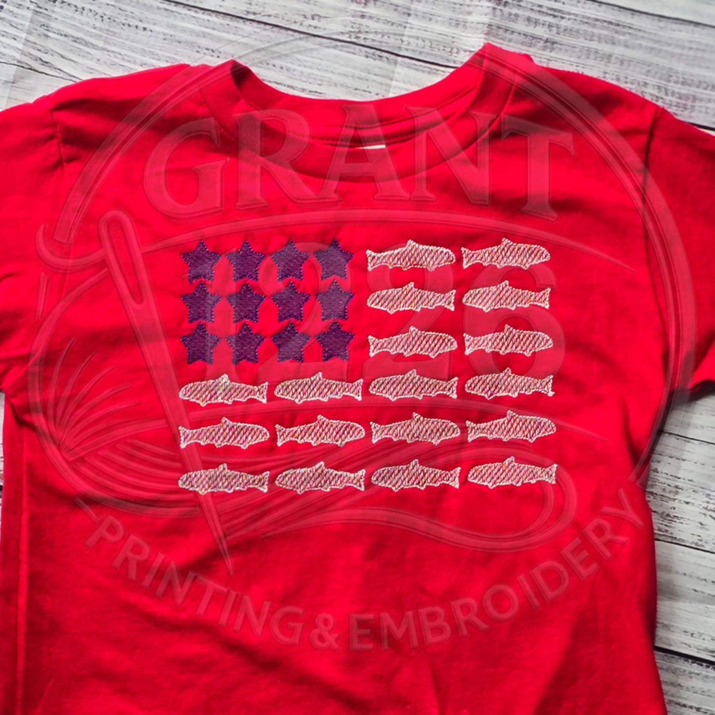 Red toddler fish flag shirt shown flat with full chest embroidery.