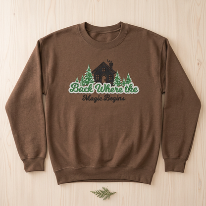 Brown Savanna crewneck sweatshirt flat-lay mockup with cabin, evergreen trees, and Back Where the Magic Begins embroidery