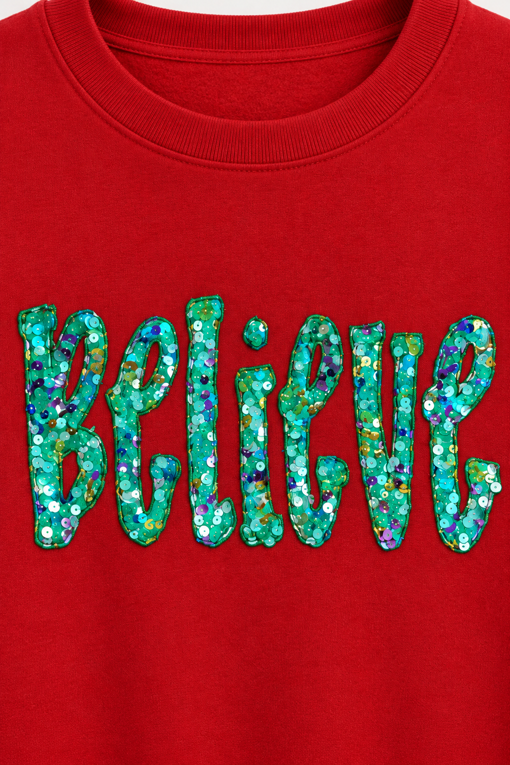 Mockup close-up of Believe multicolor sequin appliqué on a red crewneck sweatshirt