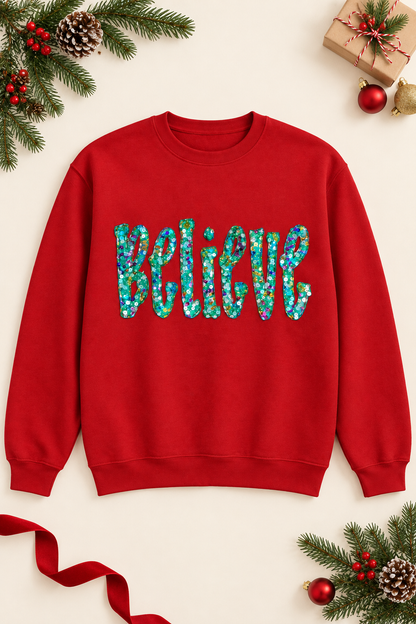 Holiday flat-lay mockup of a red Believe sequin appliqué sweatshirt with evergreen accents